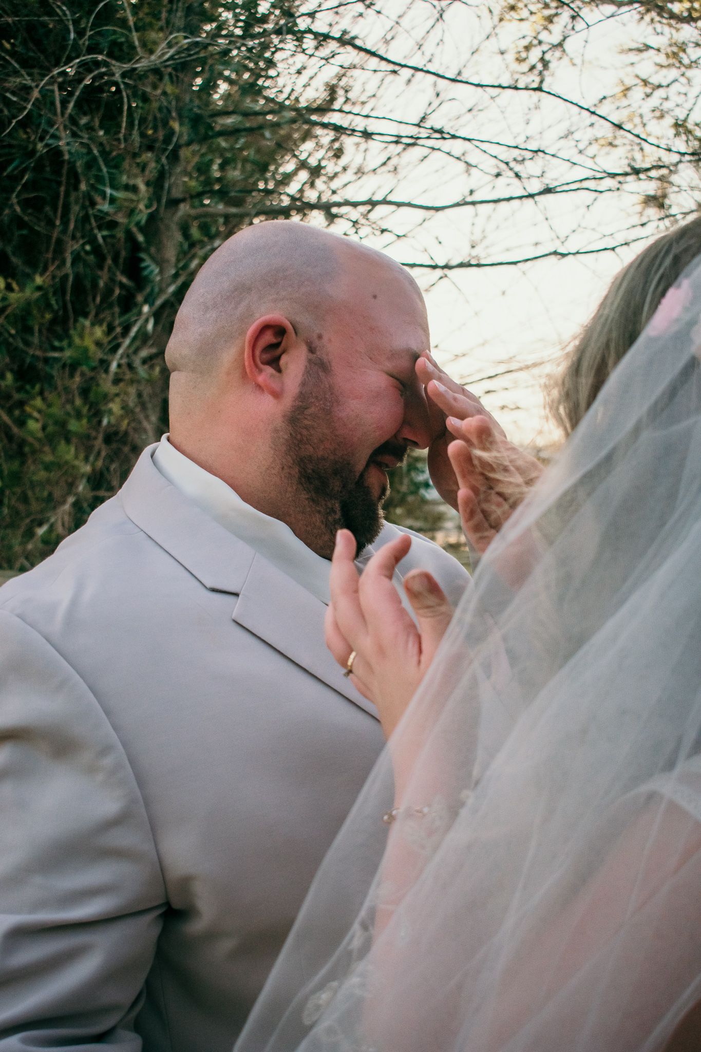 An emotional wedding portrait showing an intimate moment between newlyweds during outdoor photography session.