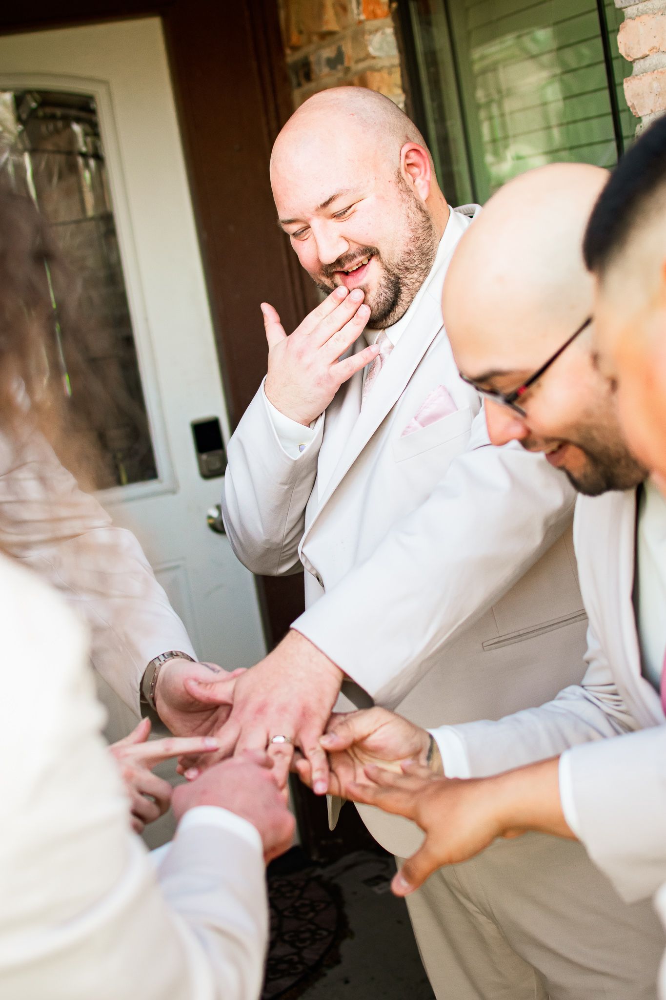 A joyful wedding ceremony moment showing ring exchange between people wearing white formal attire.
