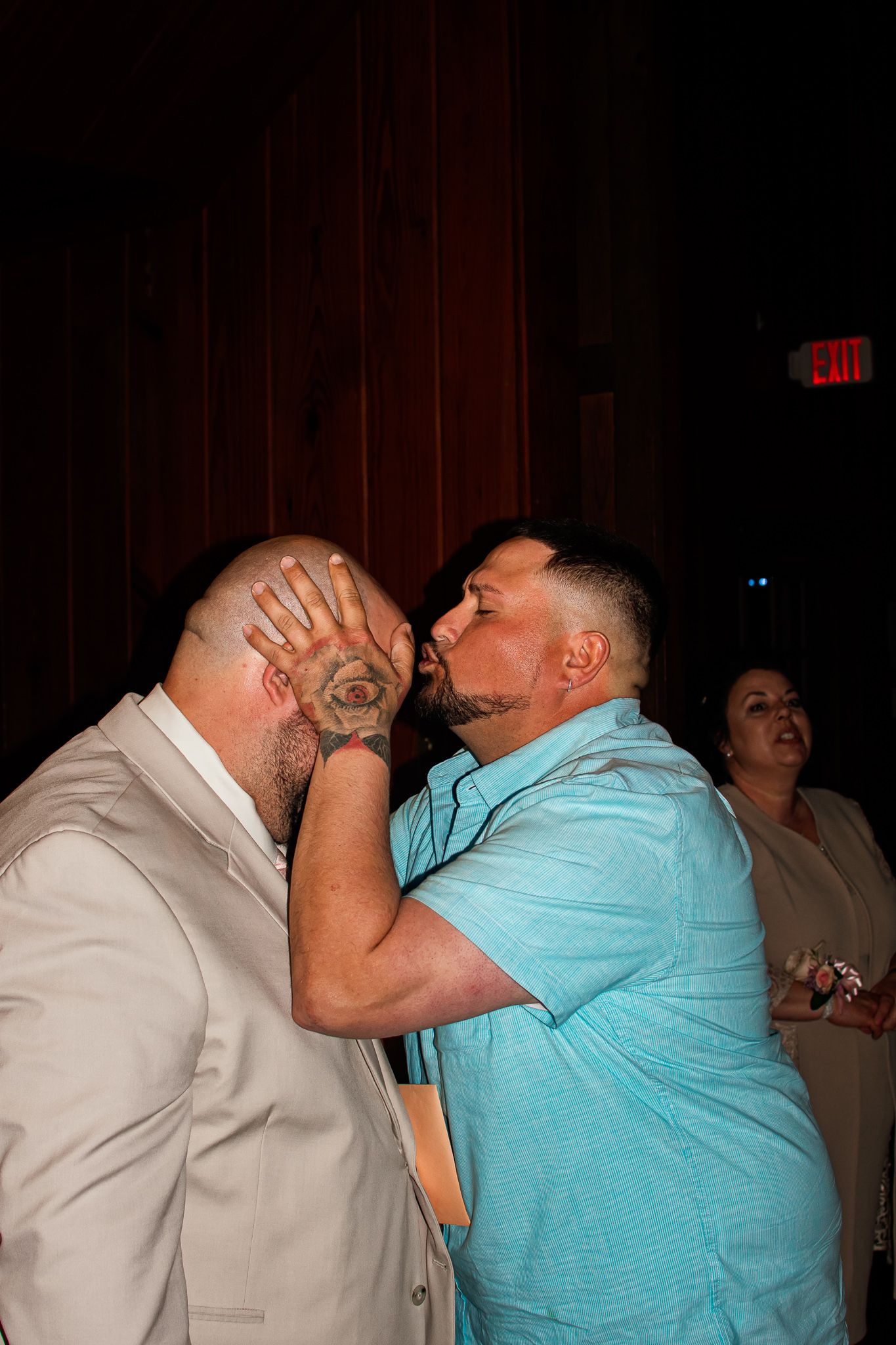 Two men in casual attire playfully embrace at what appears to be a party or social gathering.