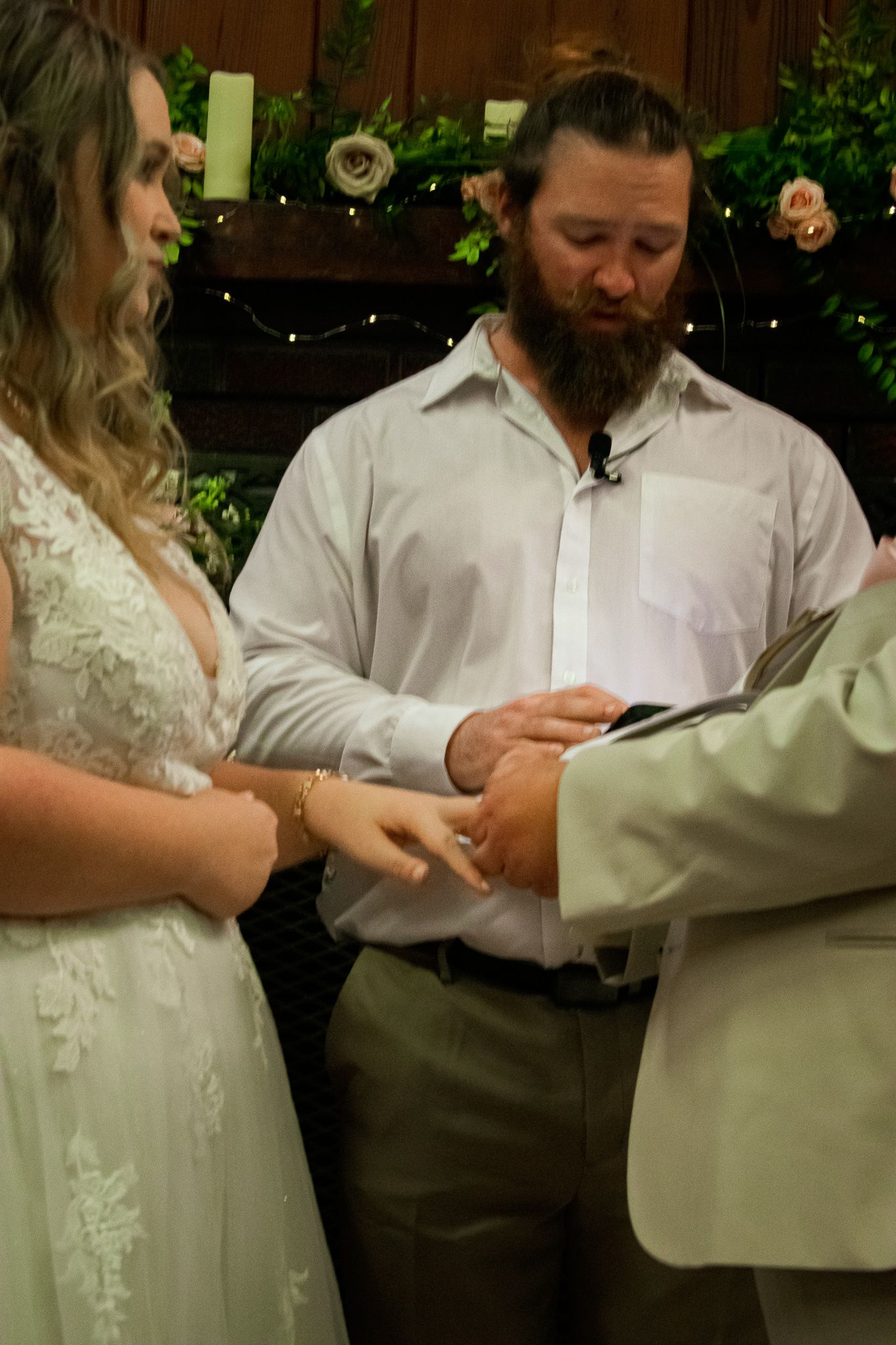 A wedding ceremony in progress with participants exchanging rings in a rustic decorated venue.