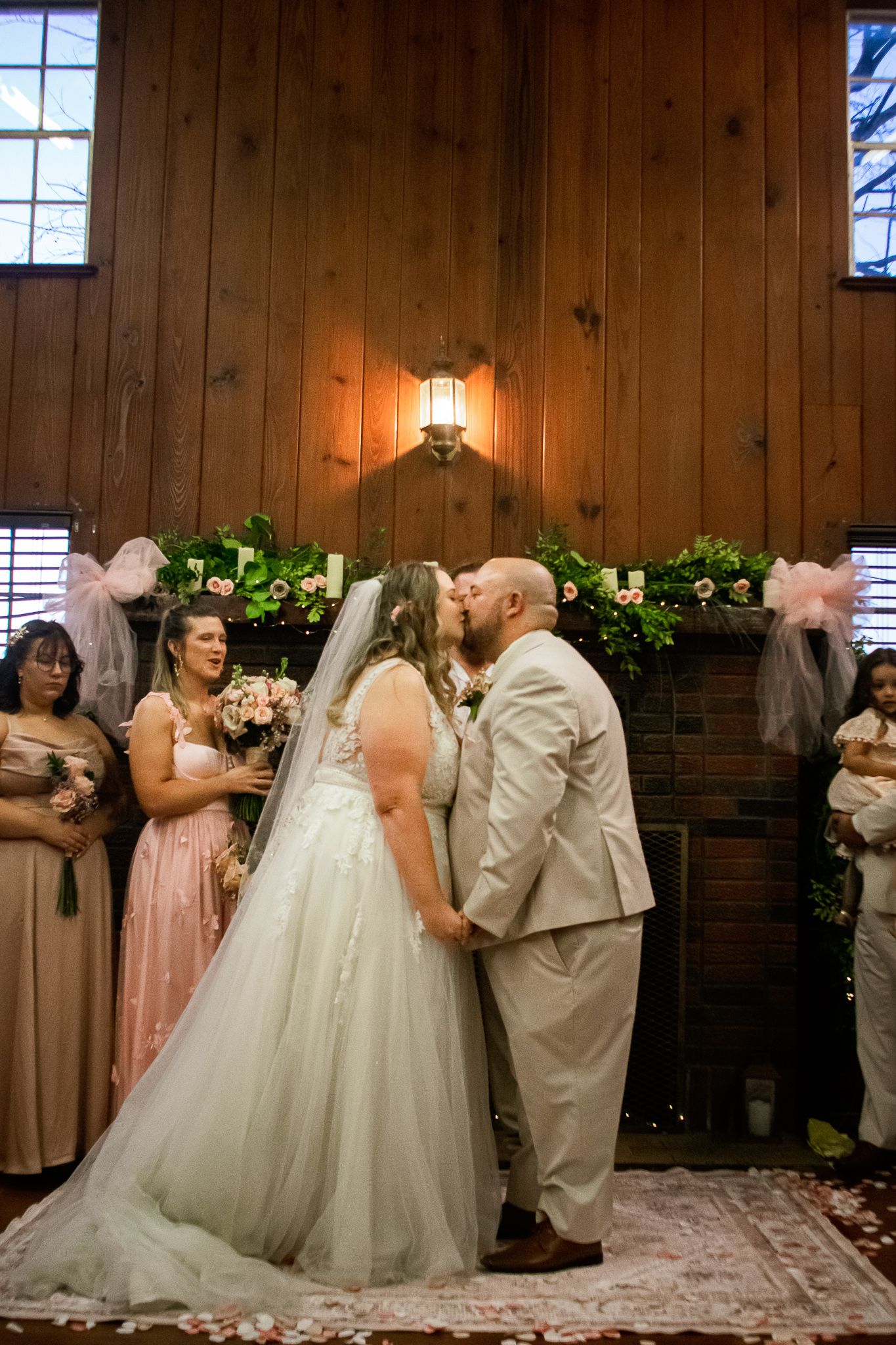 Indoor wedding ceremony with wooden panel backdrop and warm lighting.