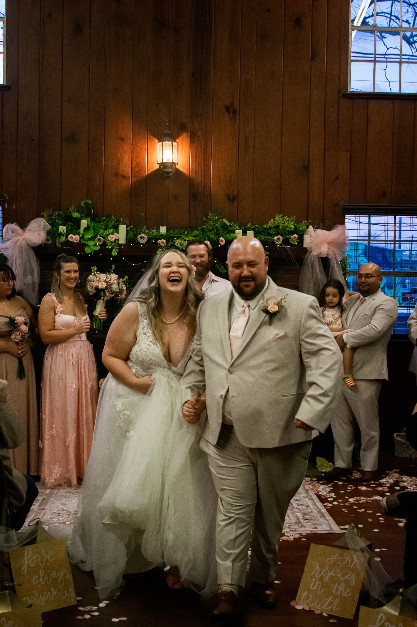 Wedding celebration in a rustic wooden venue decorated with lights and greenery.