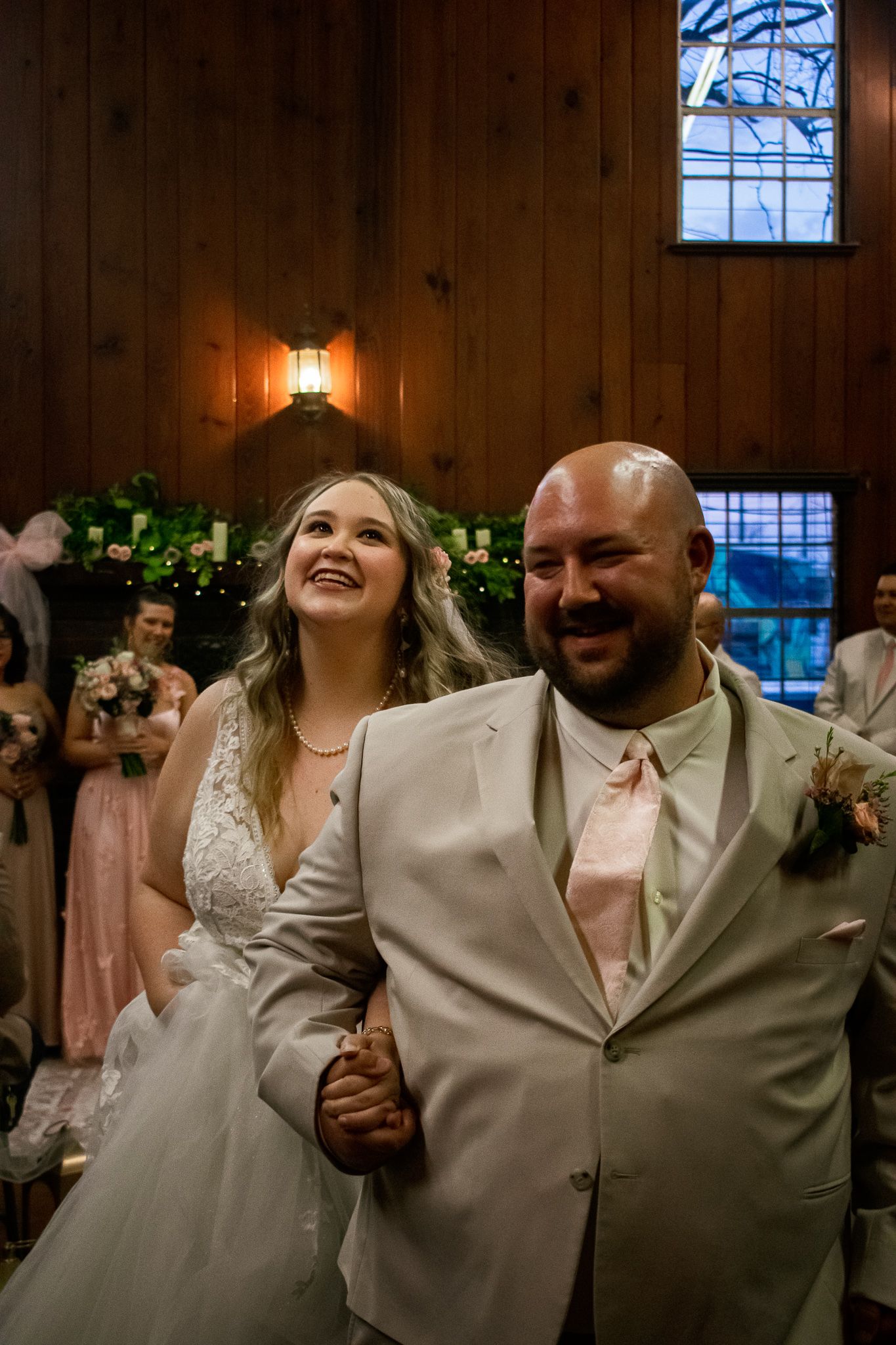 A joyful couple shares a special moment during their wedding celebration in a rustic wood-paneled venue.