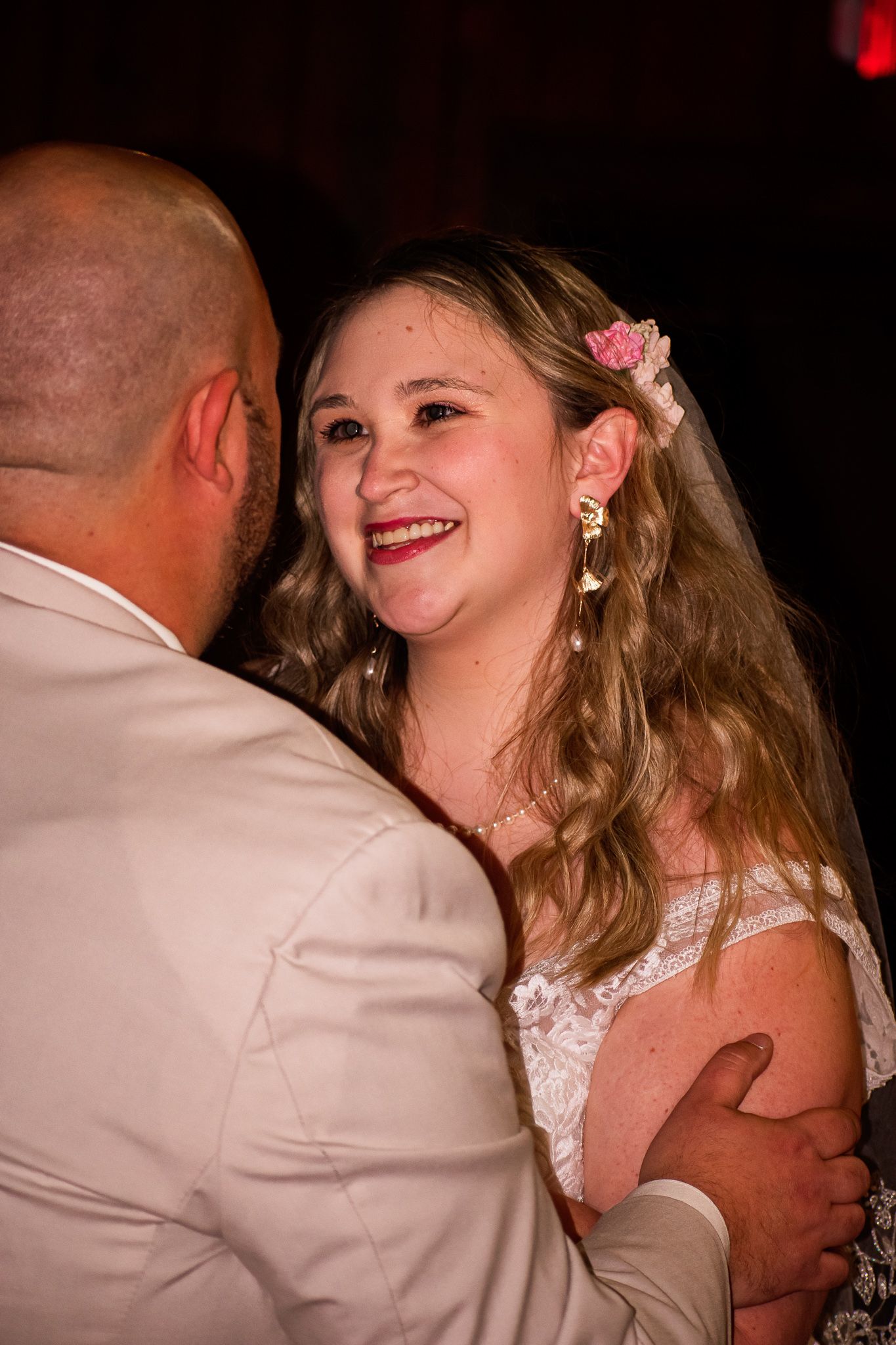 A couple dances intimately together at their wedding reception in warm lighting.