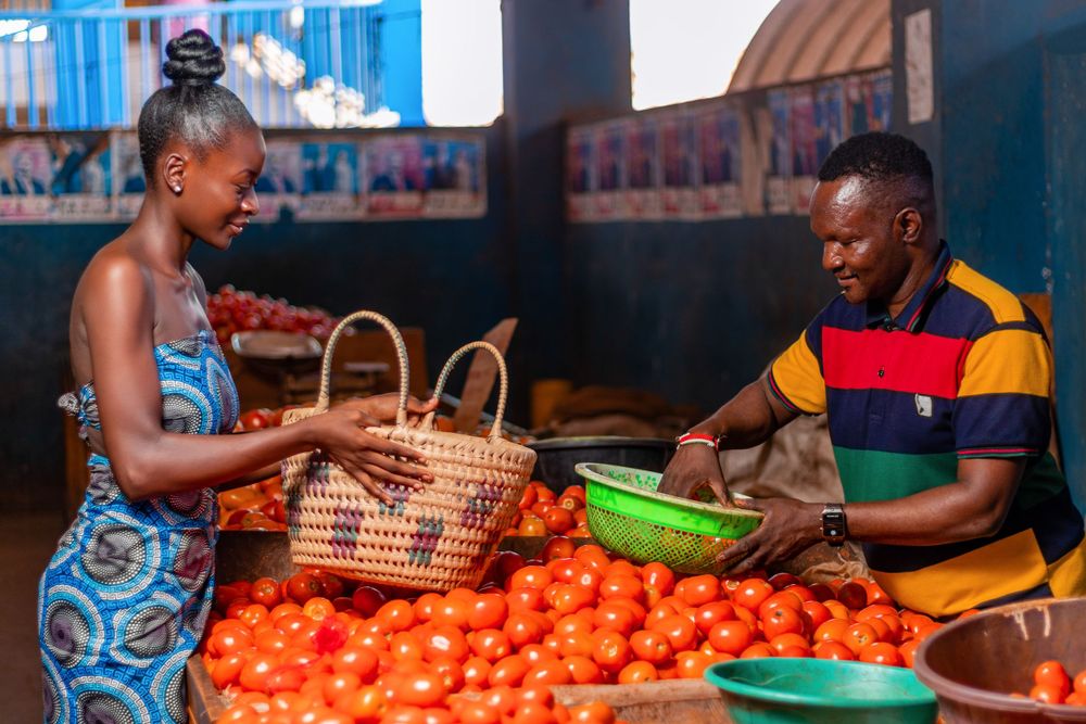 Lady with a basket buying tomatoes at a grocer vendor.