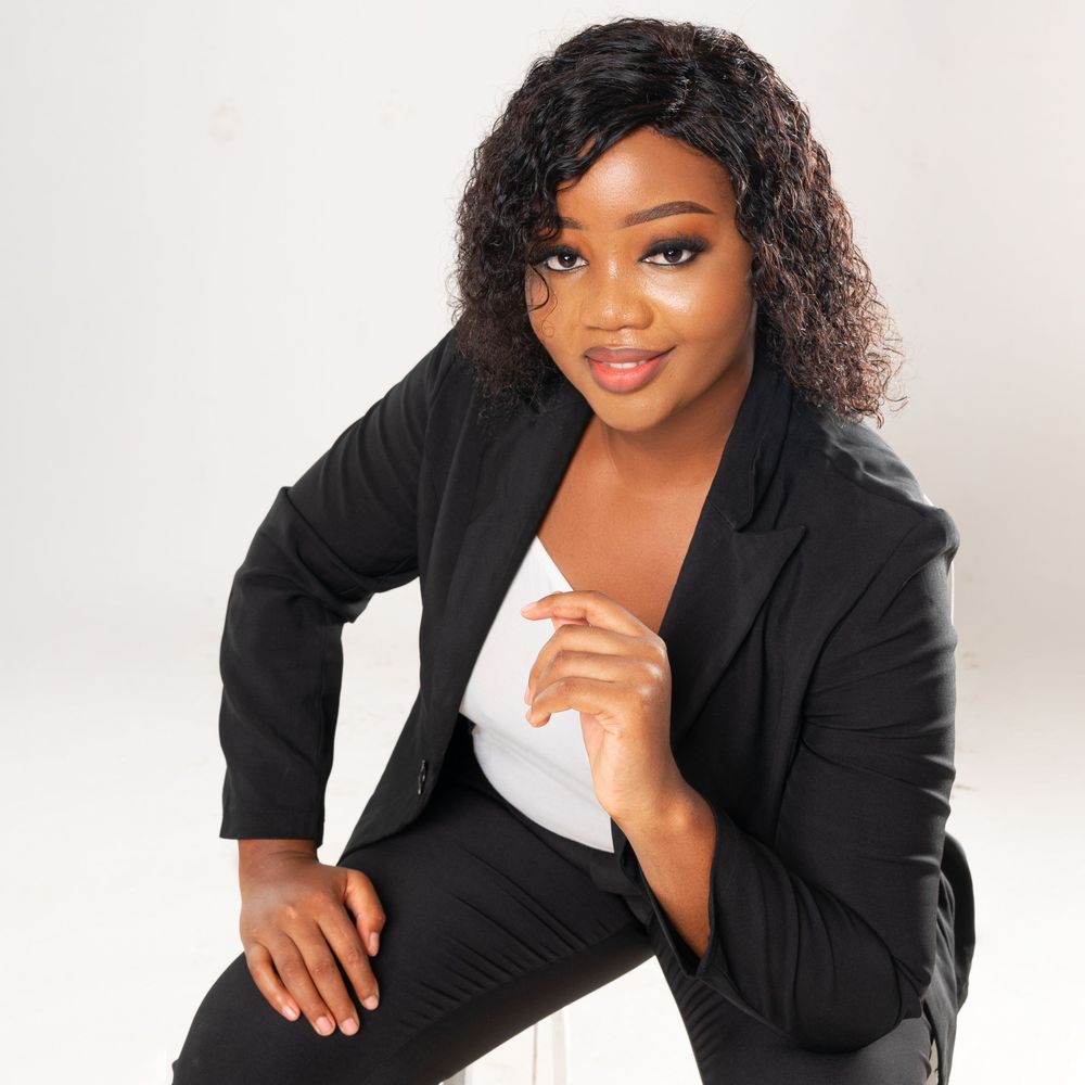 Lady in black suit seated for a photo is  shot on high angle in relation to the subject.