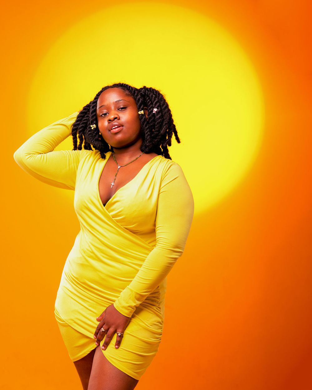 A lady with a yellow dress shot against yellow-orange hue background with a circle on the backdrop.