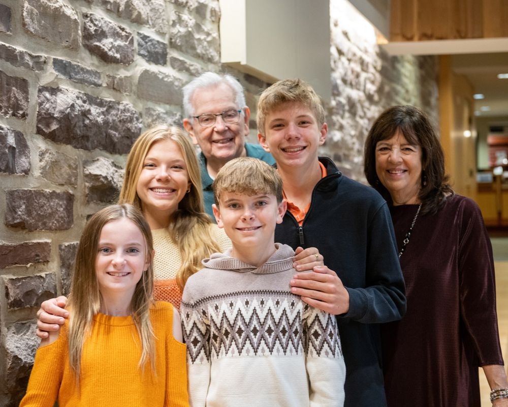 Family poses together in front of a textured stone wall indoors.