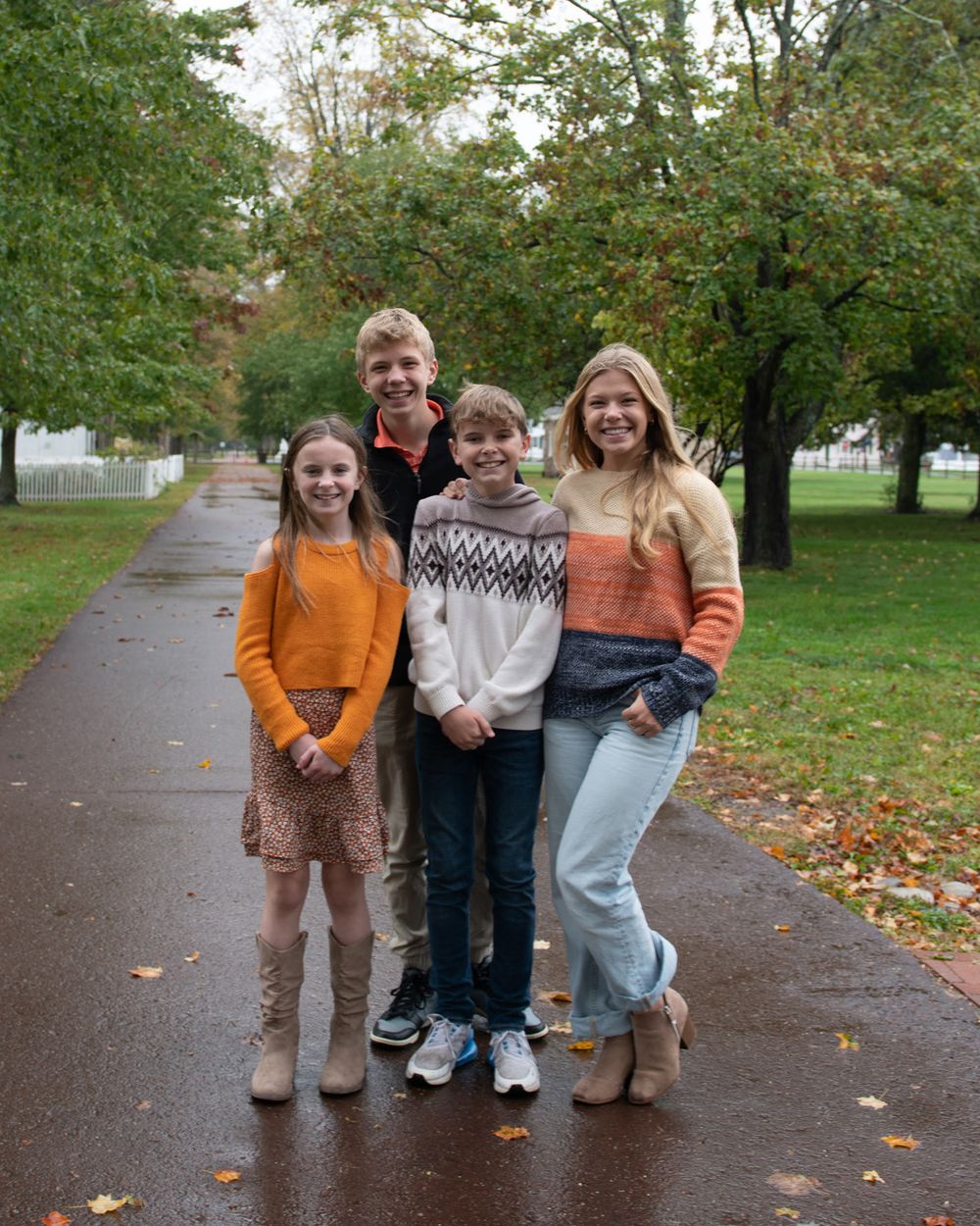 Three people standing together on a wet path surrounded by fall trees.