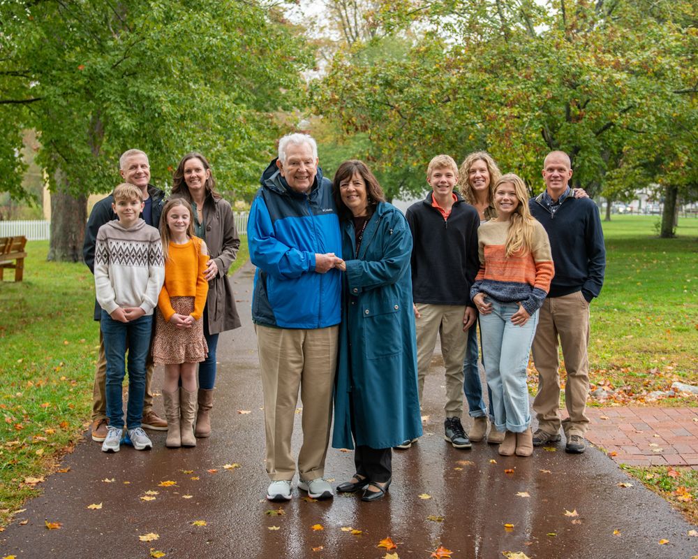 Extended family group gathered on a tree-lined path during autumn.