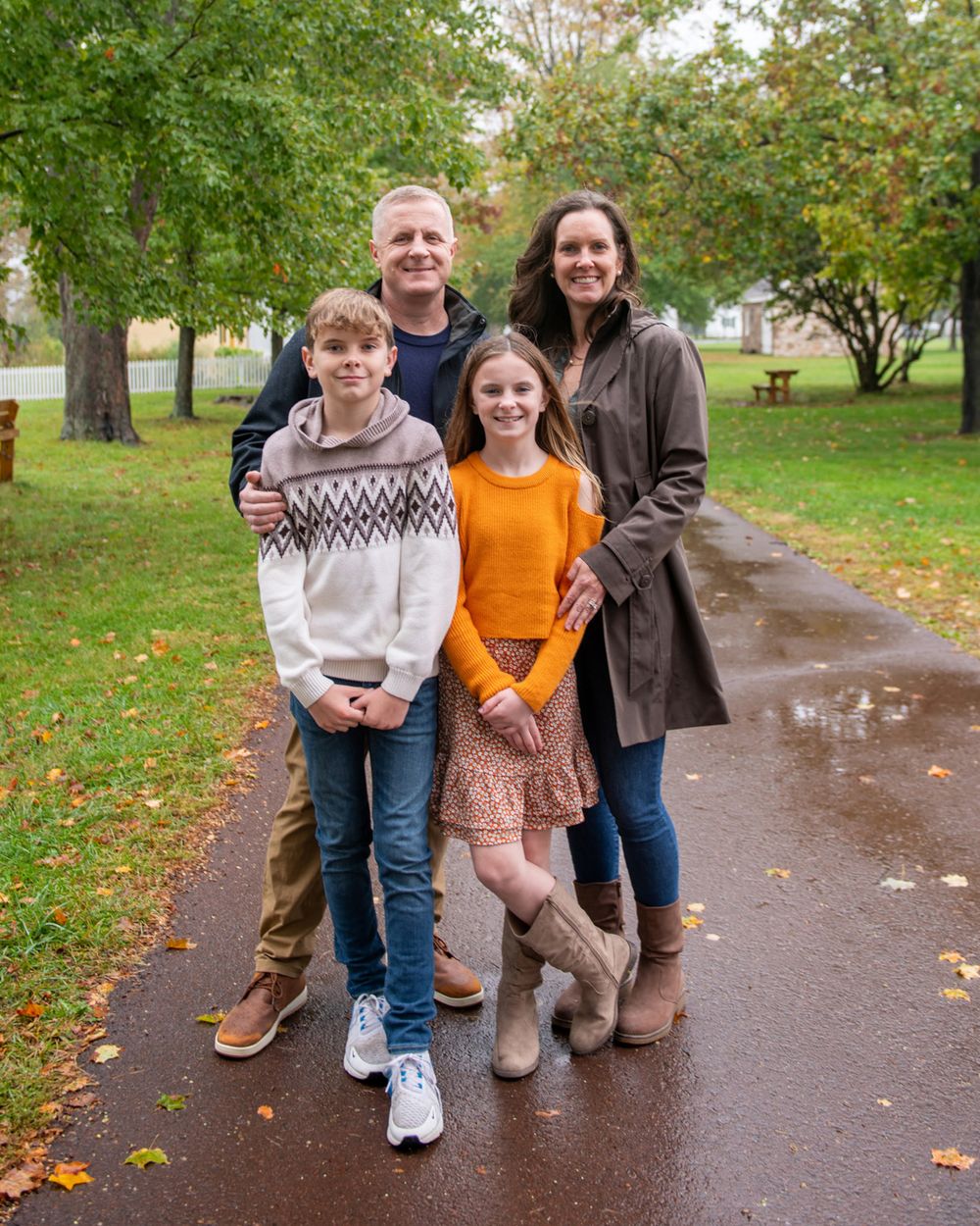 Small group standing together on wet path with autumn trees in background.