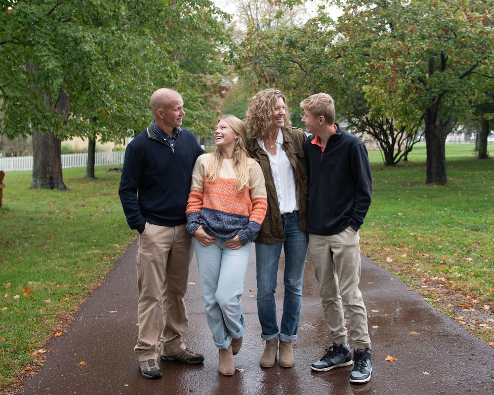 Small group standing together on tree-lined path during fall season.