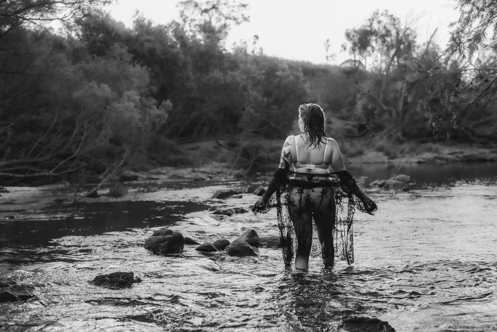 Artistic black and white photo of person wading through rocky stream.