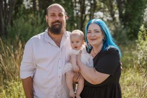 Familjefotografering utomhus med föräldrar och deras lilla barn i solnedgångsljus