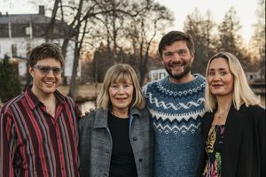 A family standing together outdoors at sunset wearing casual winter clothing and sweaters. - Fotograf Emma Matkoski