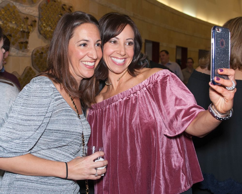 Friends taking selfies and enjoying themselves at an evening social event.