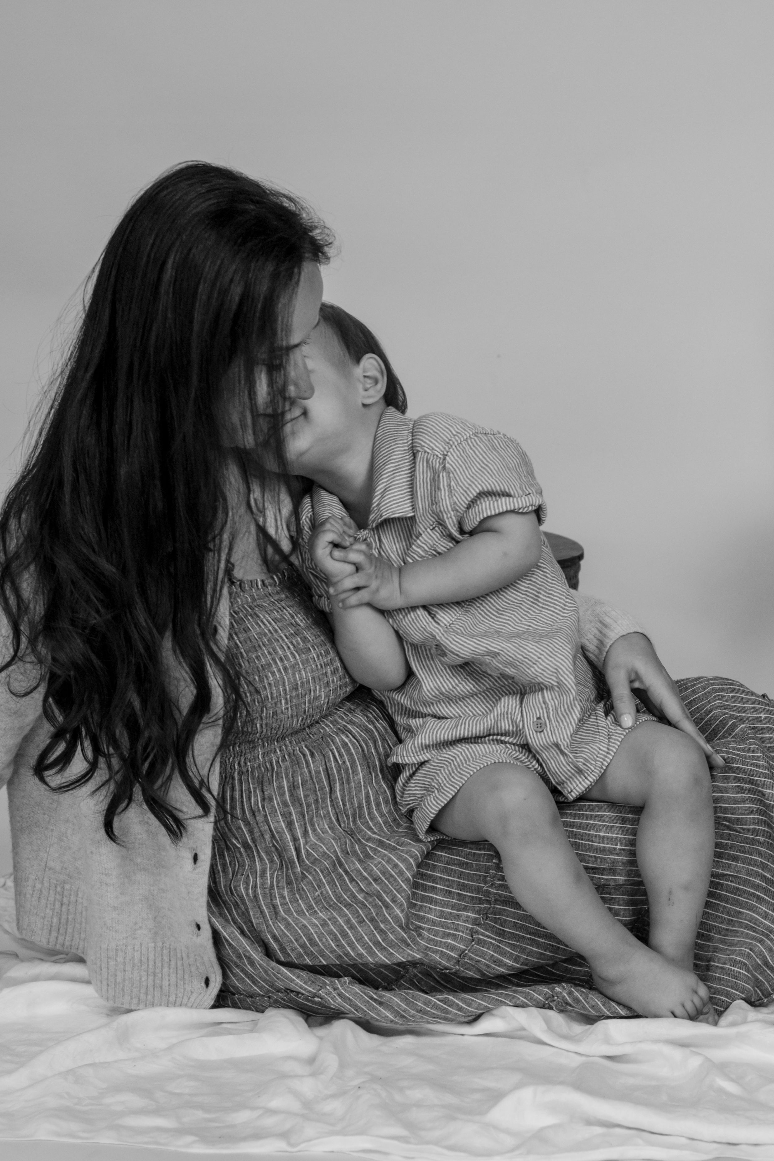 Black and white photo of mother with long hair holding sleeping baby in studio near JBLM with pierce county photographer