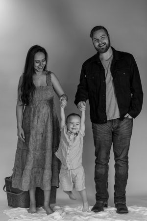 Black and white family portrait of parents holding toddler hands in photography studio with pierce county washington photographer