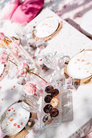 Elegant dessert table with chocolate truffles, macarons, crystal glasses, and floral decorations on a white linen backdrop.