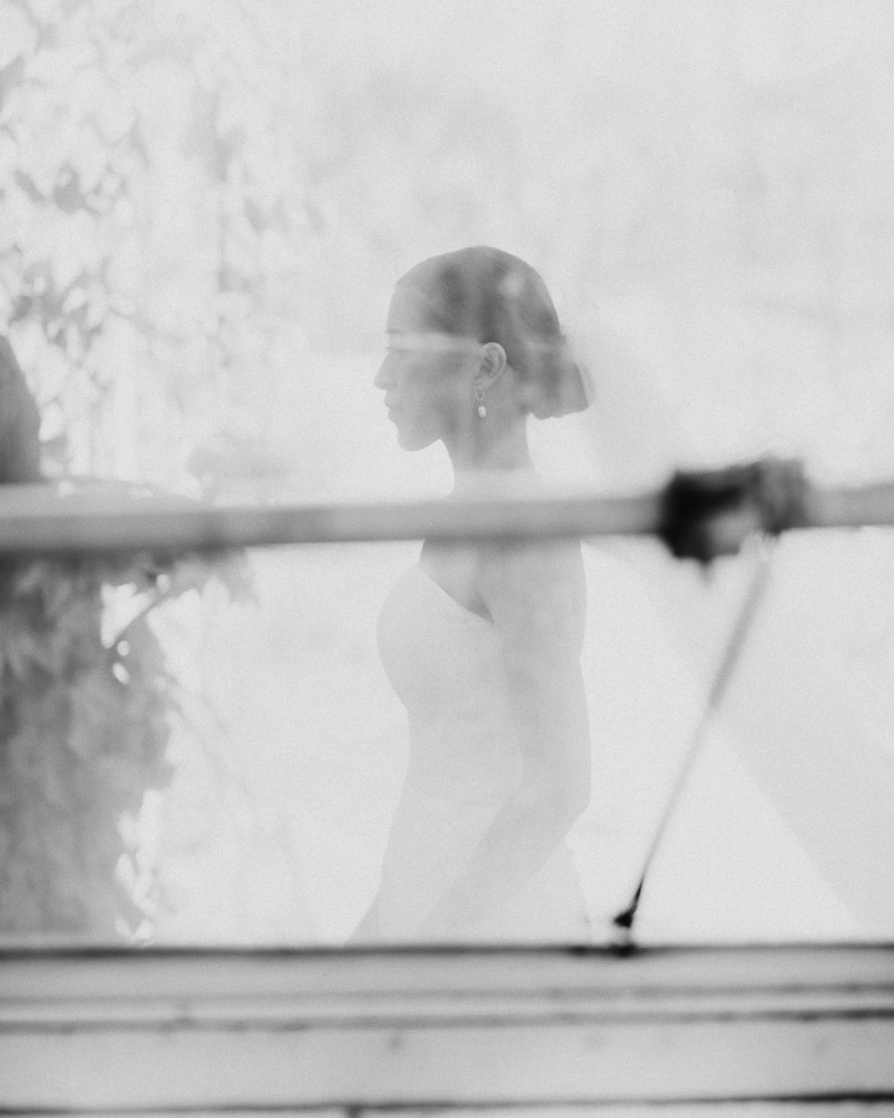 Creative monochrome wedding photo of a Filipino bride in profile wearing a veil, standing gracefully in soft diffused light.