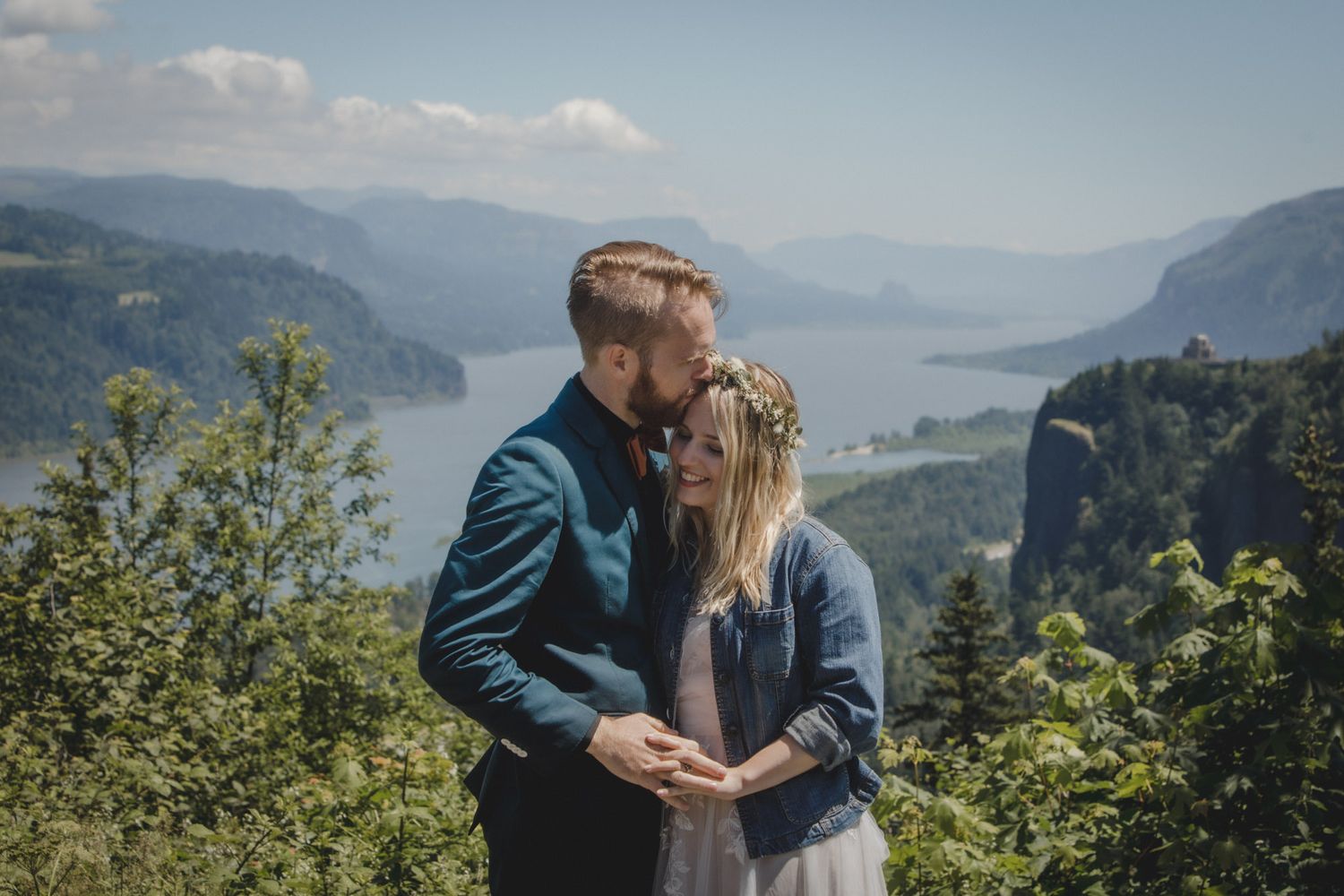 Couple sharing a romantic moment with a flower crown, overlooking the Columbia River Gorge on a sunny day.