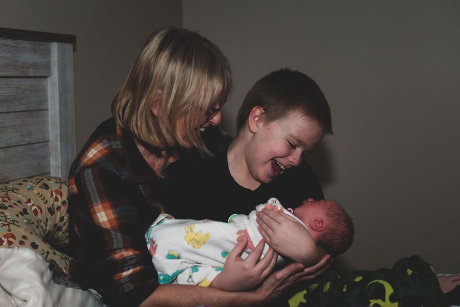 Family sharing intimate moment with newborn baby while resting in bed.
