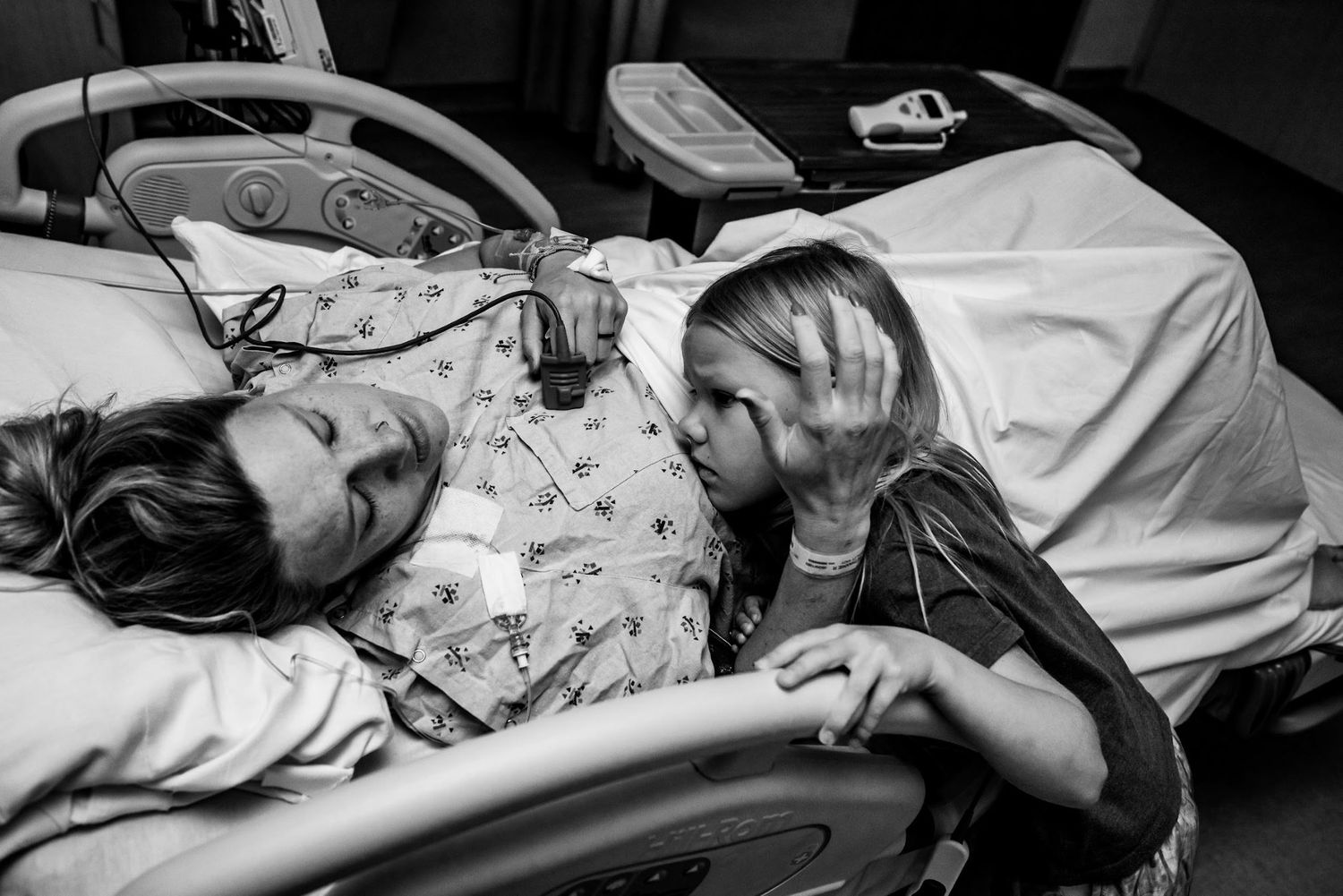 Medical professionals and attendants gather around a hospital bed during labor and delivery.
