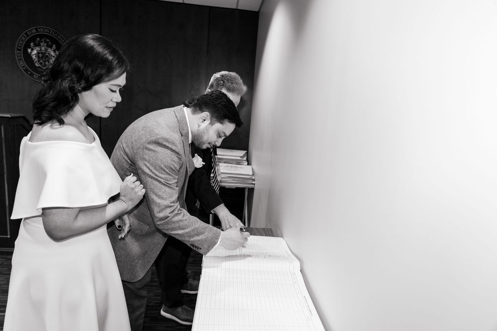 Couple signing marriage documents at a civil ceremony in black and white photo.