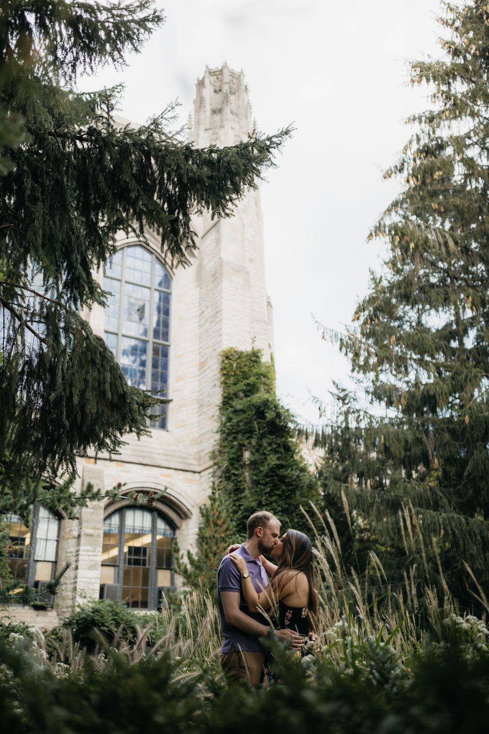 Couple kissing in lush garden of Northwestern University grounds during engagement session