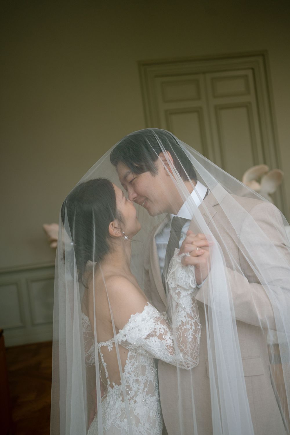 A bride and groom share an intimate moment under a flowing white veil. Paris veil wedding photos in museum. Paris editorial wedding photo