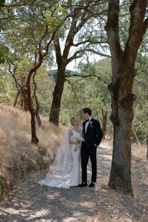 A couple shares an intimate moment under oak trees during their outdoor wedding photo session.