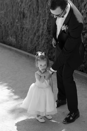 Black and white series of wedding photos showing small flower girl in white dress next to formal shoes.