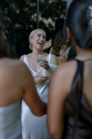 Wedding guests enjoying drinks and laughter during an elegant outdoor reception celebration.