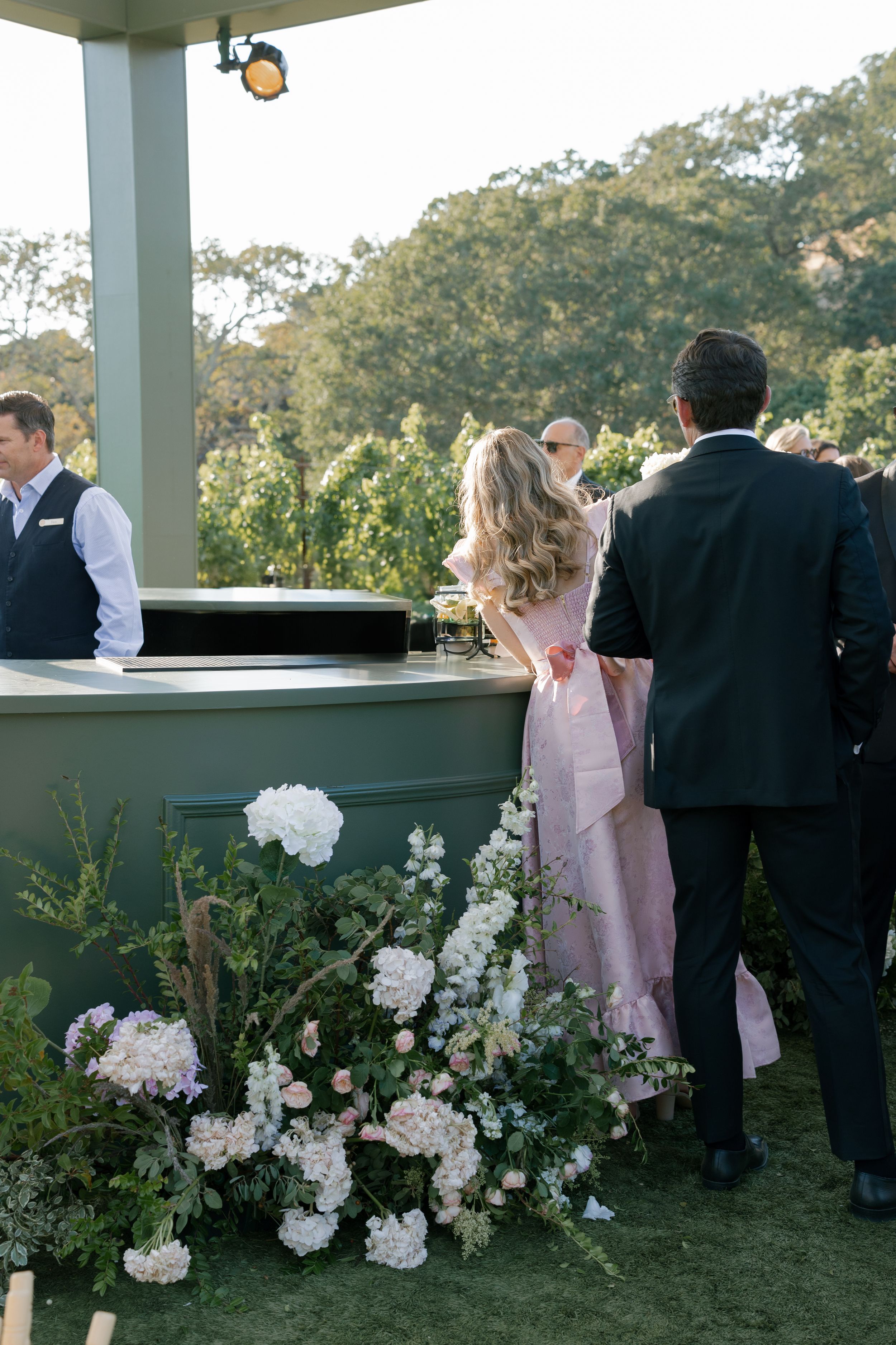 Elegant outdoor wedding reception with white floral arrangements decorating a covered patio area at sunset.