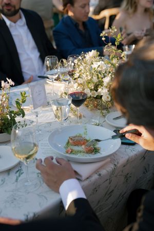Elegant table setting with delicate floral centerpieces and white plates at an upscale dinner event.