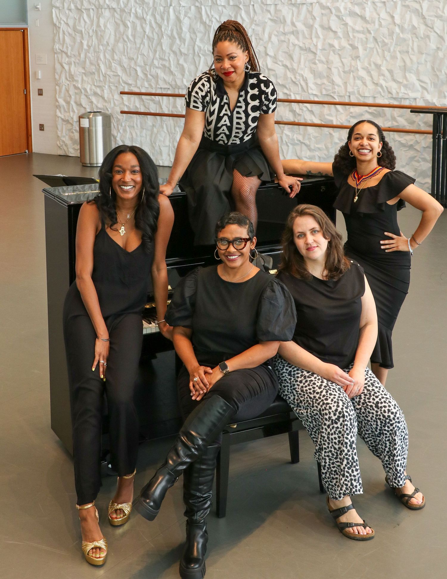 Five women engaged in a lively panel discussion seated on chairs in a modern, well-lit studio space.