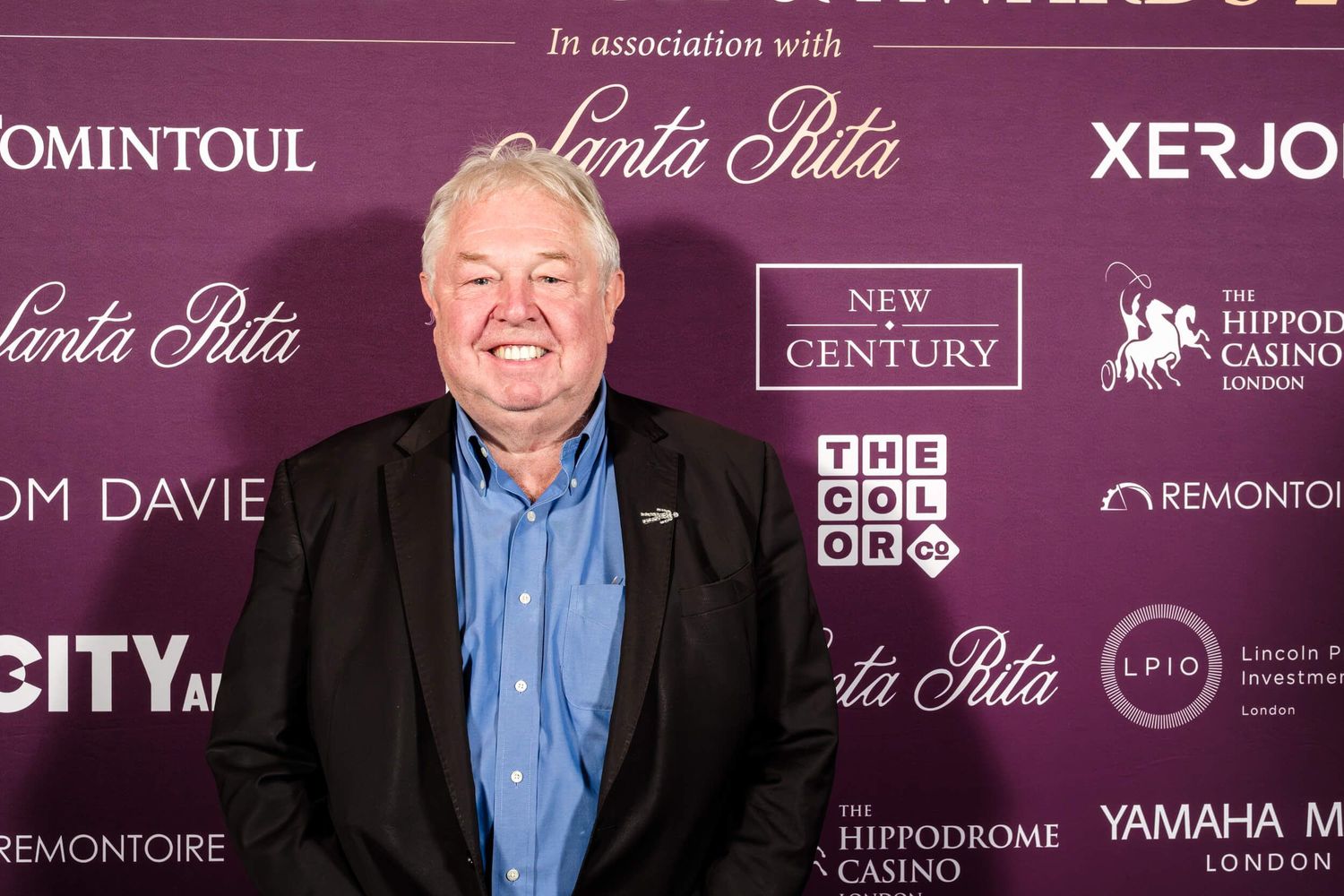 Purple-tinted backdrop wall displaying sponsor logos and branding for an upscale event.