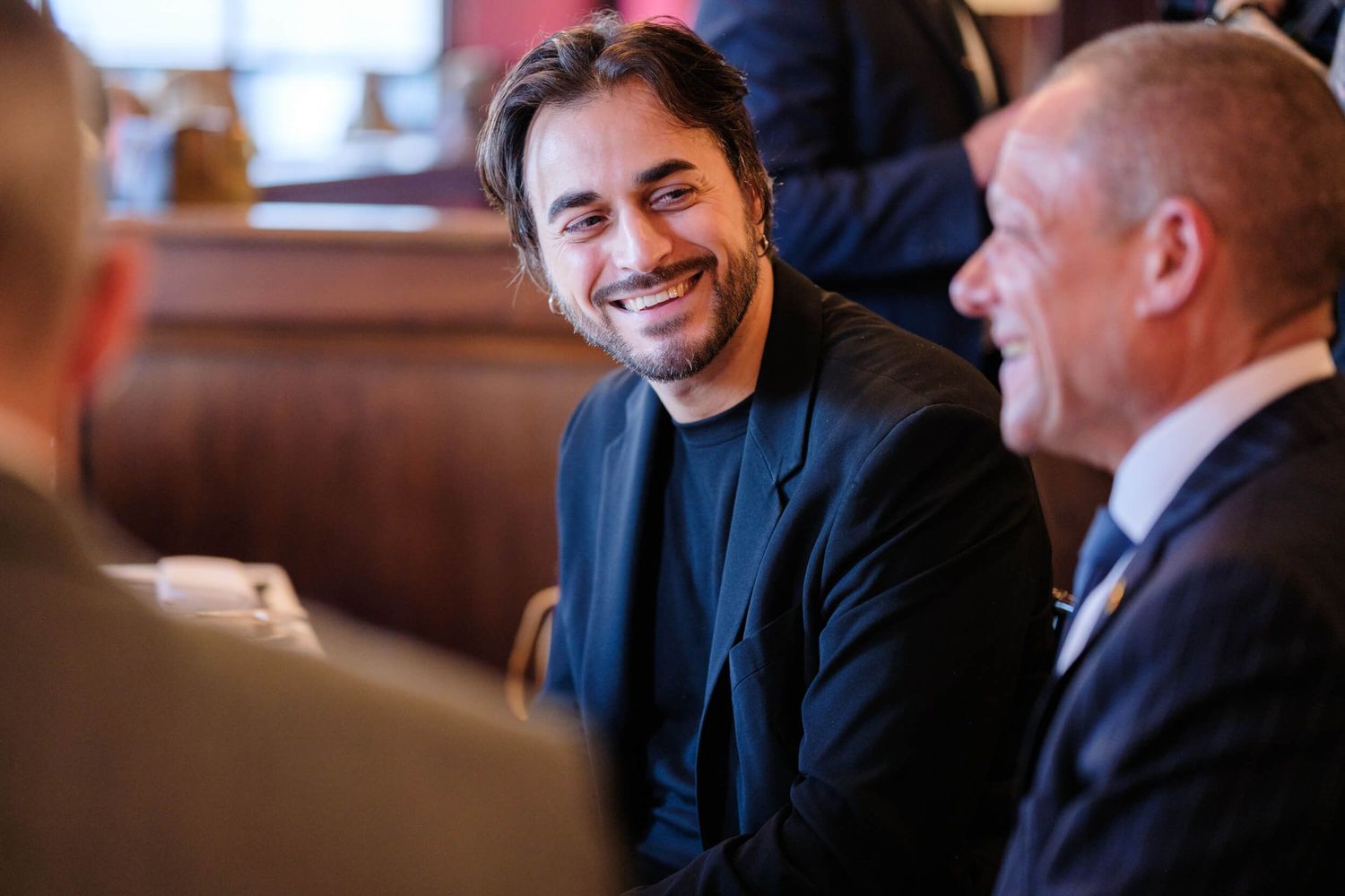 Two people in business attire having an engaged conversation at a restaurant table.