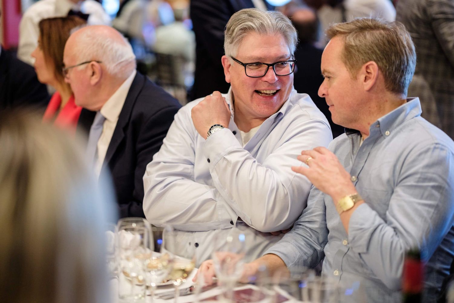 Two people share a laugh while dining together at a restaurant table.