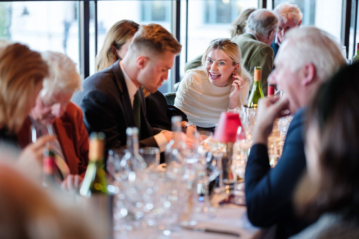 Guests seated at long tables participating in a wine tasting event with multiple glasses.