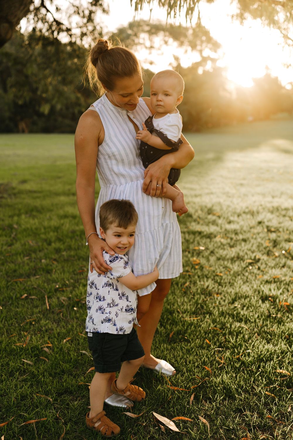 A mother with her children in golden sunset light at an outdoor family photography session in Perth