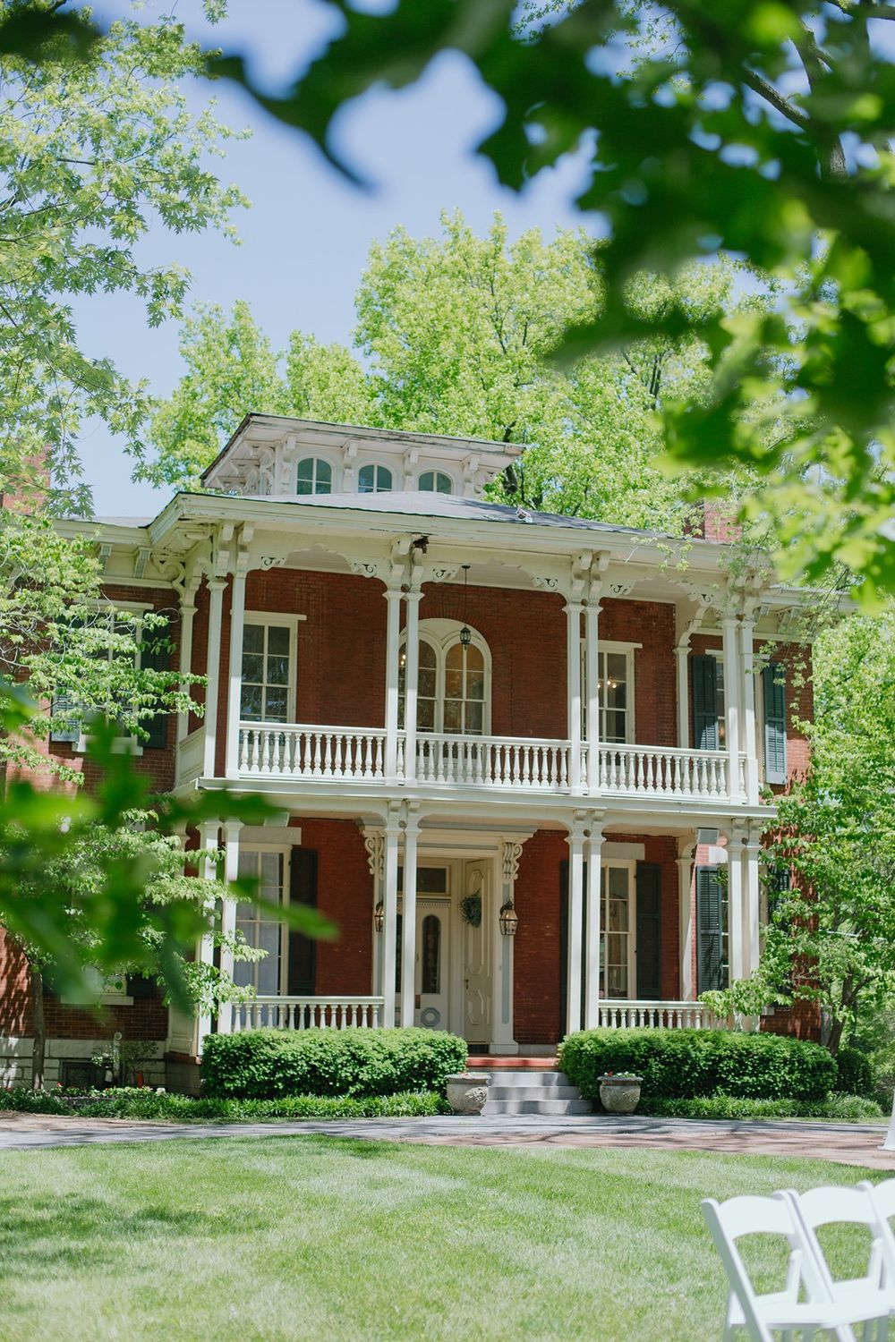 The Larimore Wedding Venue on a spring day, with green leafy branches covering the top right corner.