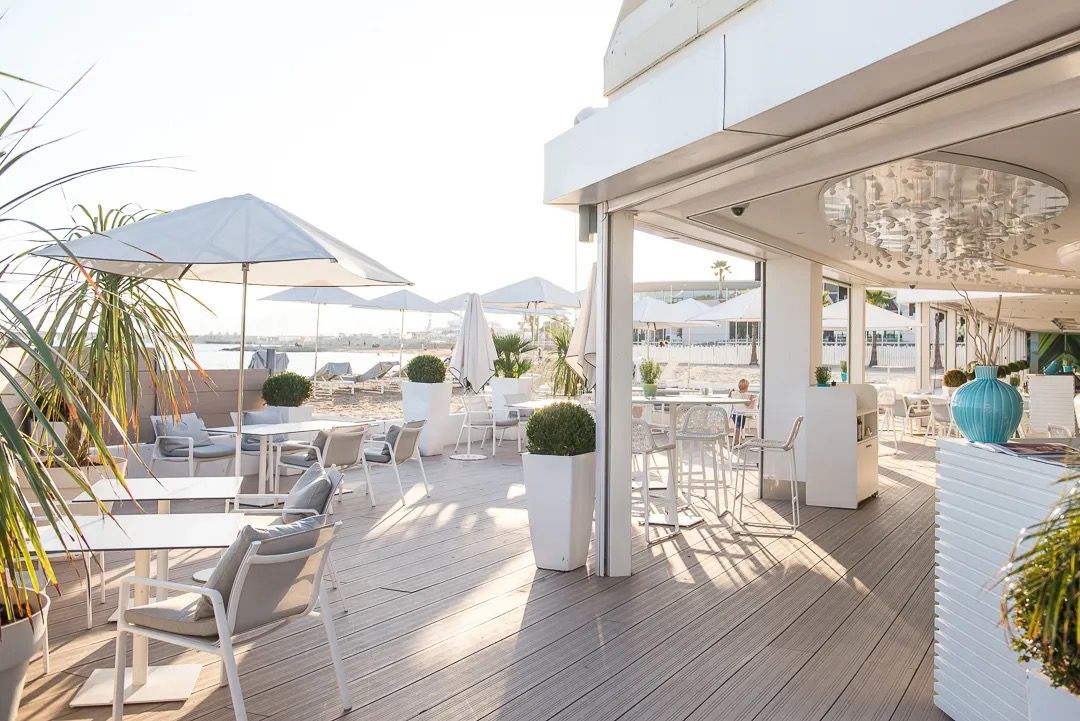 A bright beachside restaurant with sun loungers, white parasols and sea views.
