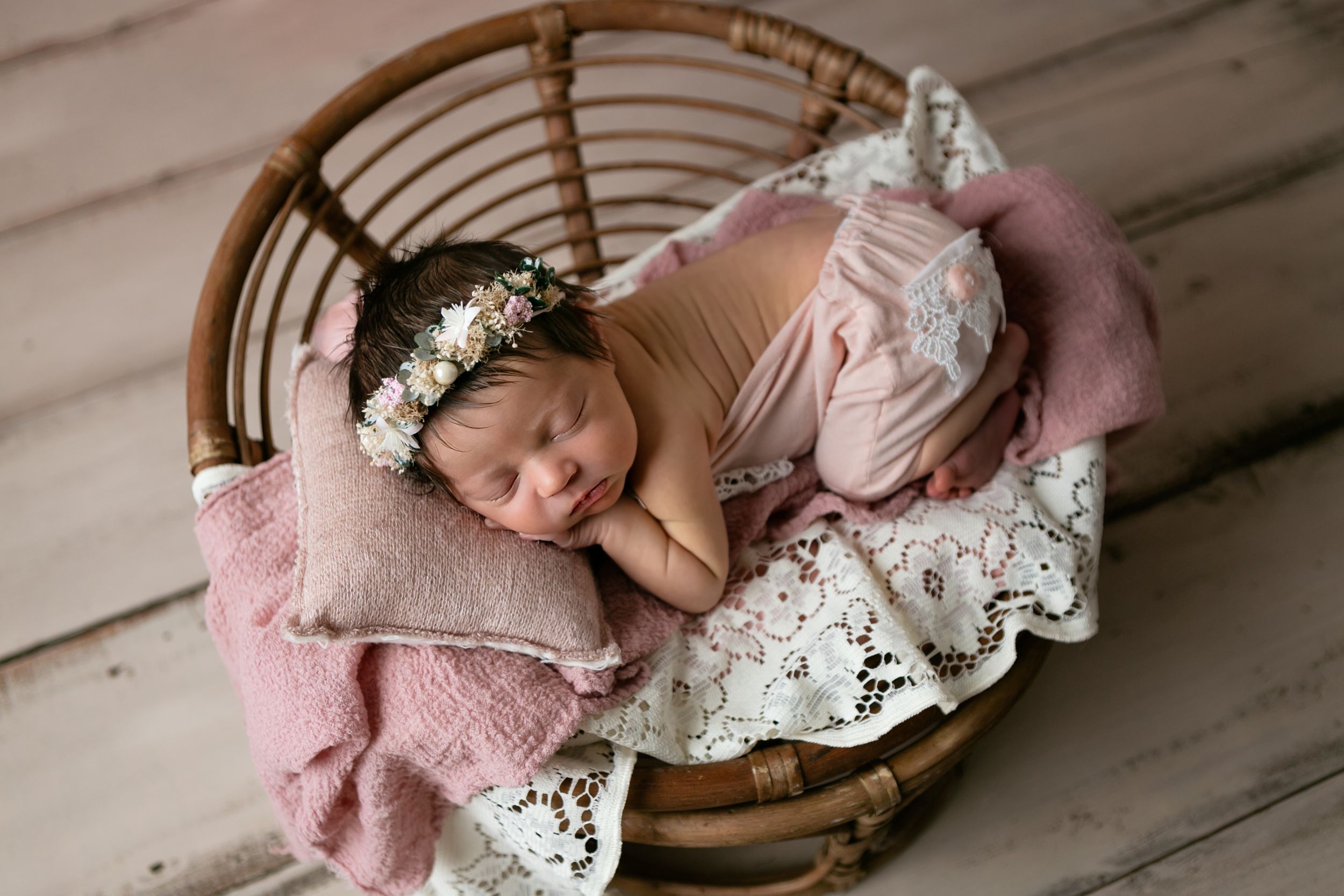 A sleeping newborn in a pink wrap lies in a basket surrounded by white lace. Orlando Newborn Photography, Sanford Newborn Photography