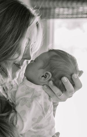 Black and white series of mother tenderly holding and kissing newborn baby.