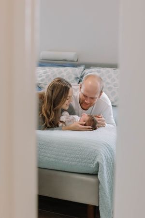 Family lying together on bed sharing intimate moment with newborn.