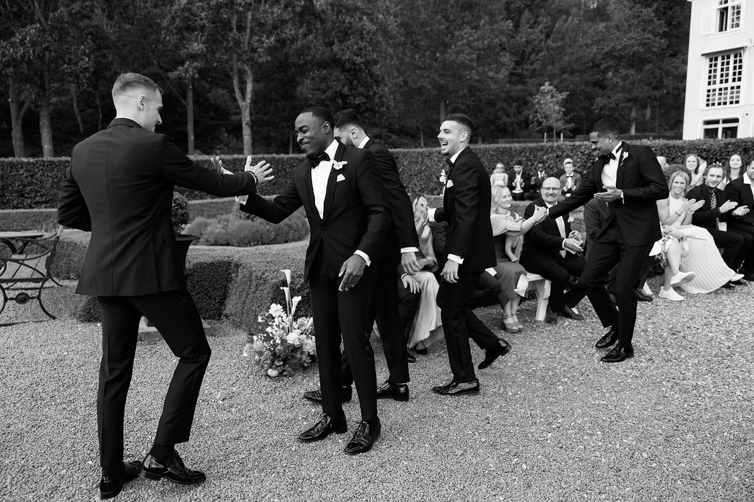 A group of dancers in formal attire perform synchronized dance moves at an outdoor event.