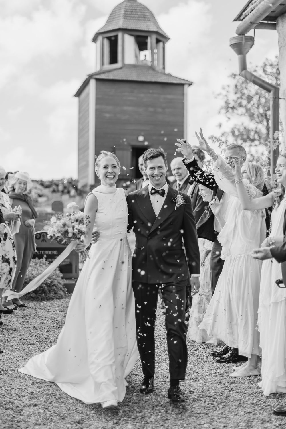 Wedding celebration with guests throwing confetti at a rustic chapel venue.