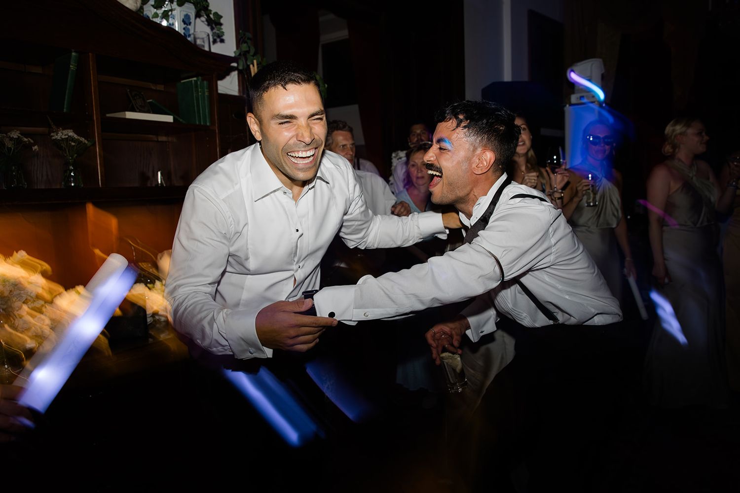 People dancing and celebrating at a party with blue lighting in the background.
