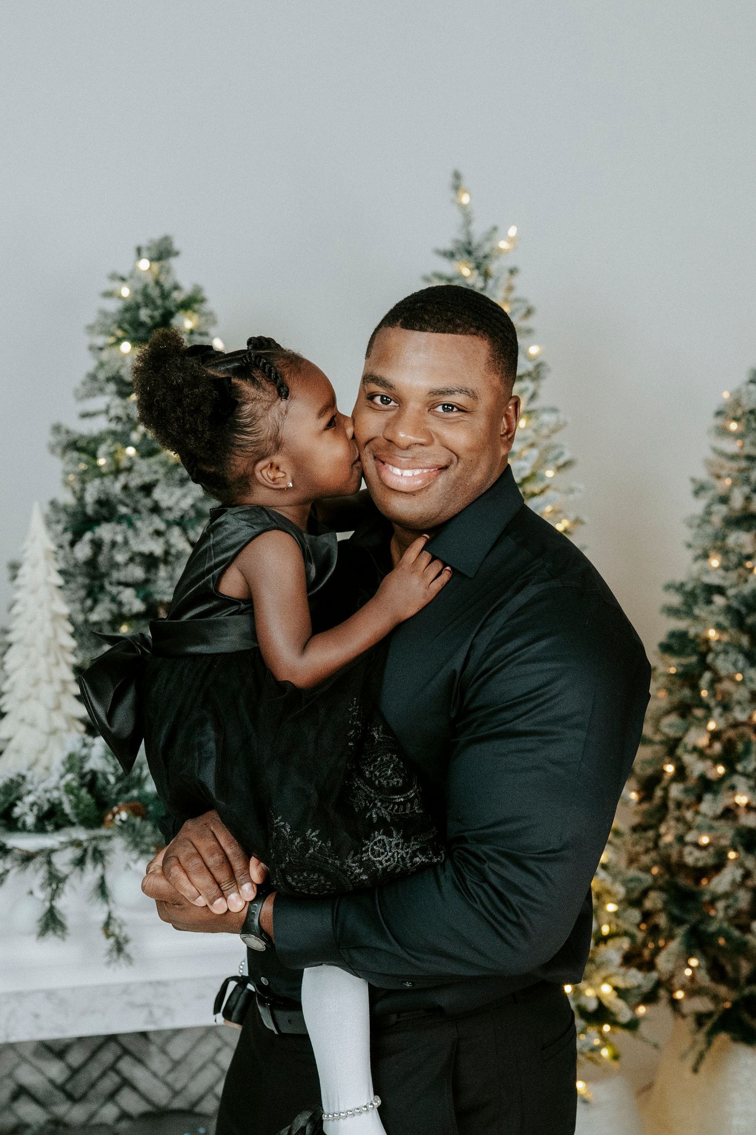 A heartwarming holiday portrait with decorated Christmas trees in the background.